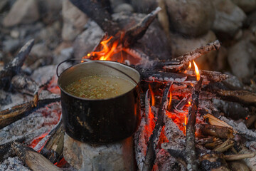 Far Eastern nature. Close-up. Tourist bowler hat stands on the fire. Cooking tourist soup over the...