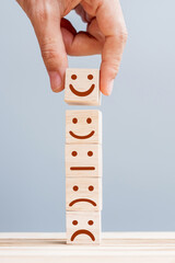 Hand holding smile face symbol on wooden cube blocks. Emotion, Service rating, ranking, customer...
