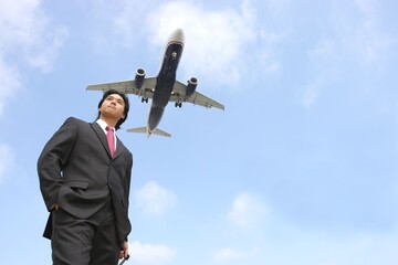 A large passenger plane passing over a young businessman heading to the airport