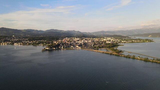 Aerial drone shot flying sideways over lake Zurich looking over Rapperswil at sunset in summer