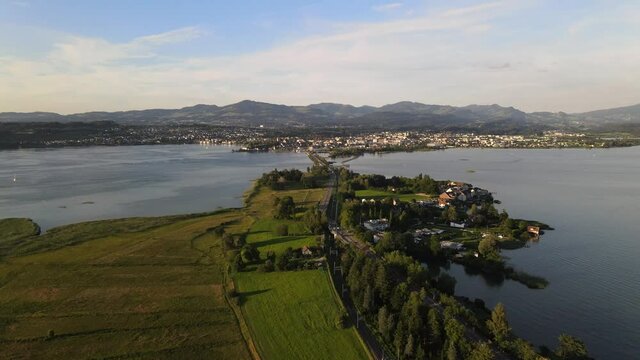 Aerial drone shot flying sideways above Hurden overlooking and flying towards Rapperswil at sunset in summer