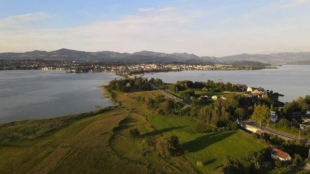 Aerial drone shot flying backwards revealing Rapperswil and Hurden during a summer sunset