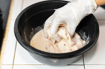 Cook marinate spieces and chicken in black bowl.