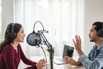 Smile two asian young woman, man radio hosts in headphones, microphone while talk, conversation, recording podcast in broadcasting at studio together. Technology of making record audio concept.