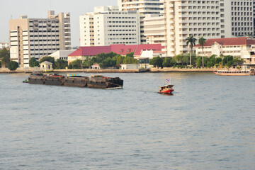 Obraz premium Sand boat pulled by a tugboat is shipping in the Chao-pha-ya river form Ayu-tha-ya province to Bangkok is a long time local transport business in Thailand.