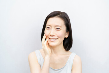 顔を触る日本人女性（40-50代のイメージ）