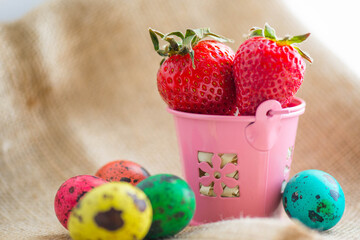 Easter eggs and strawberries in a pink bucket