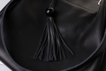 Close-up of a black leather bag with a decorative element of a tassel with an acrylic bead