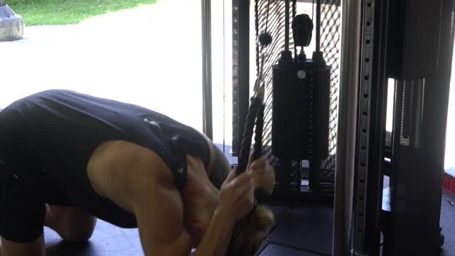 Muscly man in home gym exercising cable crunch ab workout