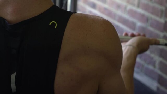 Tattooed muscly man in home gym working out close up shot from behind lat row