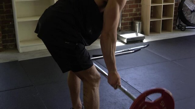 Muscly man in home gym exercising close grip barbell row