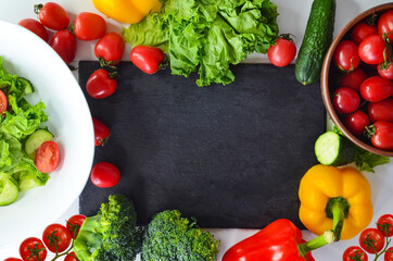 food background with copy space for text, vegetable ingredient for cooking on a stone board, tomatoes, cucumbers, lettuce, sweet peppers, salad in the bowl, broccoli