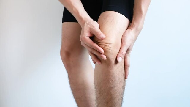 Knee pain .man sitting on the bed  Her hand caught at the knee. Having painful feet and stretching muscles fatigue To relieve pain. health concepts.