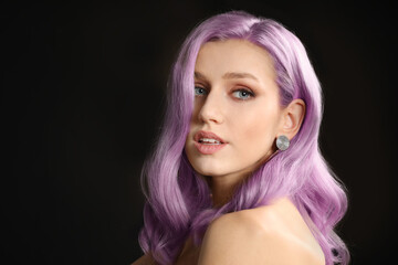 Beautiful young woman with unusual hair on dark background