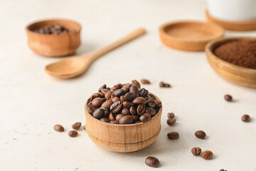 Bowl with coffee beans on light background