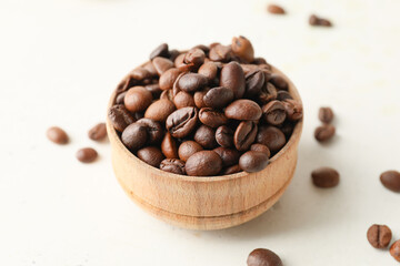 Bowl with coffee beans on light background