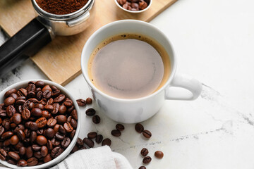 Cup of coffee and bowl with beans on light background