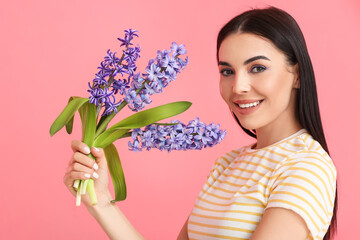 Beautiful young woman with hyacinth flowers on color background