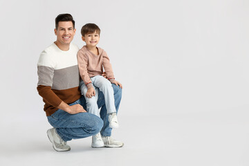 Happy father and his little son on light background