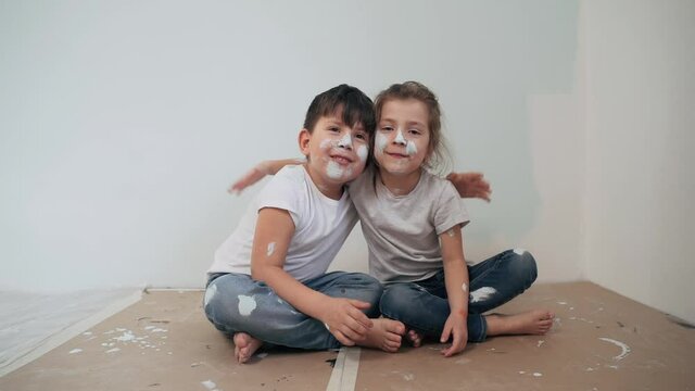 Caucasian kids paint the walls Boy and girl took a break and have fun Children's faces are painted Boy hugs girl Twins make repairs Funny kids Happy family Slow motion