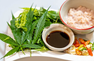 Ingredient for stir-fried hot and spicy pork, with basil, chili,  garlic, and cannabis leaves. Selective focus on cannabis leaves.