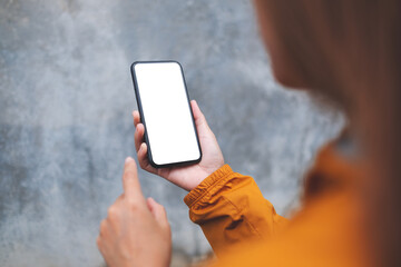 Mockup image of a woman holding mobile phone with blank white desktop screen in the outdoors