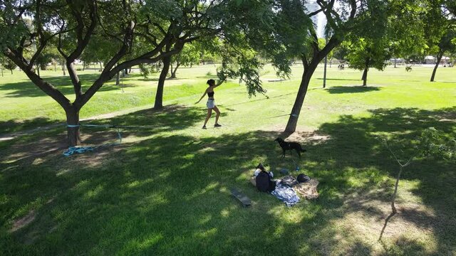 Aerial shot of young woman balancing on slack line at the park