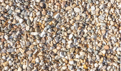 Mix colors of pebbles stone element for outdoor landscaping with natural sunlight, garden decorative. Top view, abstract small rocks pattern. Texture of nature background.