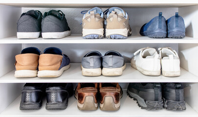 Many shoes of man and woman in different fashion style put in 3 storeys white shoe rack. Everyday footwear collection use for variety seasons and lifestyle (sport, casual and leather business shoes). - Powered by Adobe