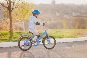 Fototapeta premium Little kid in helmet rides a bicycle on a sunny day