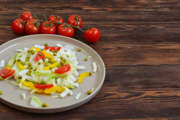 fresh summer vegetable salad with peking cabbage, cherry tomatoes, green peas and yellow bell pepper on a ceramic plate