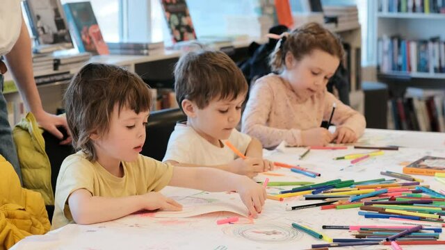 Little children draw pictures with markers in kindergarten