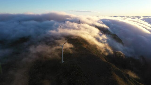 Drone aerial footage of rolling clouds over mountains with wind turbines on the island of Madeira, Portugal