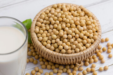 Soy and soy milk in a glass with soybeans in wooden bowl background