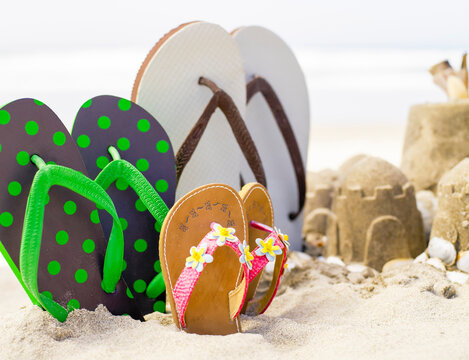Flip flops standing upright in the sand next to sandcastles