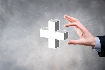 Businessman hold 3D plus icon, man hold in hand offer positive thing such as profit, benefits, development, CSR represented by plus sign.The hand shows the plus sign