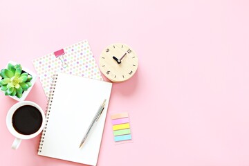 Still life office, business, planning, meeting or work from home concept : Top view or flat lay of open notebook, clock and coffee cup on pink background with copy space ready for adding or mock up 
