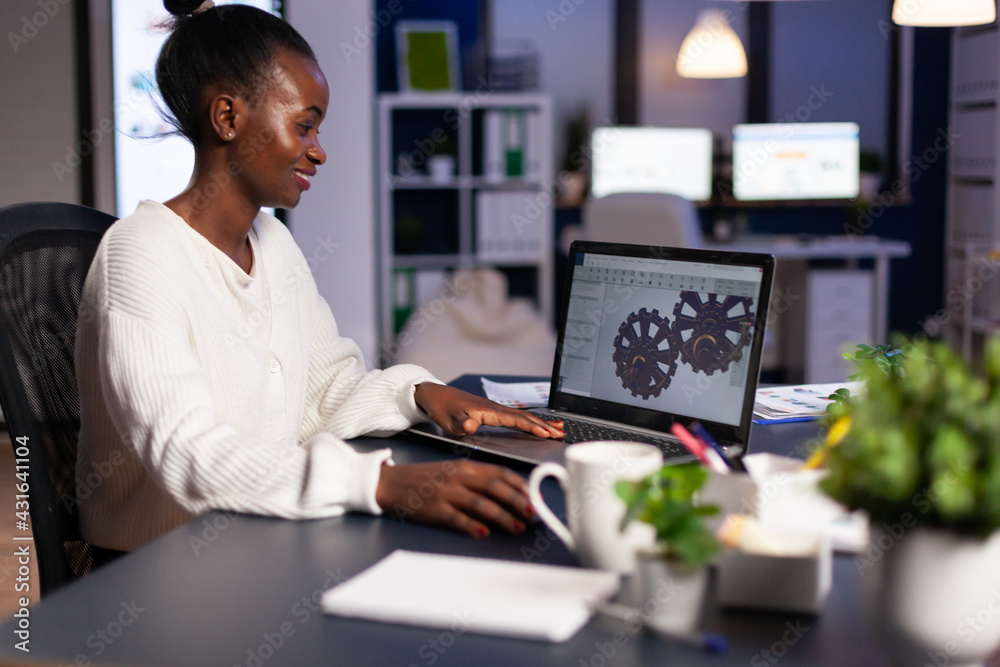 Poster african mechanical designer working on computer late at night doing overtime to finish project. free