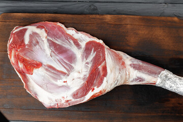 Raw beef leg on brown wooden board