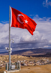 Vertical view of a large Turkish flag in Göreme, Cappadocia with the landscapes of Cappadocia in the background
