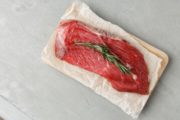 Raw beef fillet piece on wooden board close up