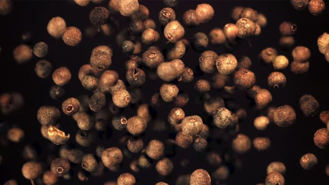 Super slow motion of black pepper peas soar upwards. On a black background. Filmed on a high-speed camera at 1000 fps.High quality FullHD footage