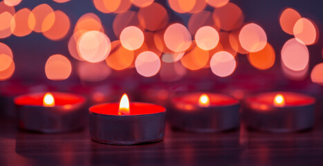 Obraz na płótnie Canvas red candles burning in front of a bokeh background