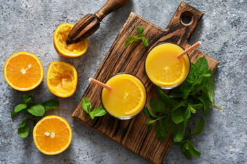 Fresh squeezed orange juice on a gray concrete background with mint.