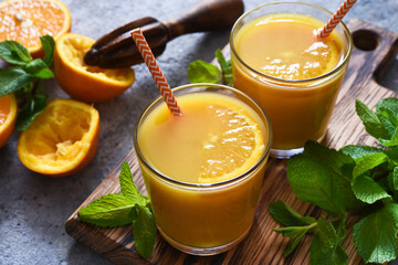 Fresh squeezed orange juice on a gray concrete background with mint.