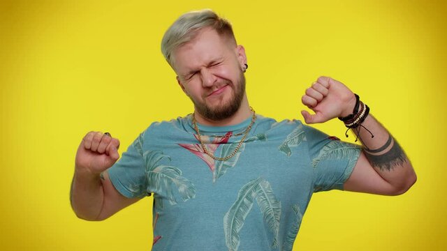 Tired handsome stylish tourist guy in t-shirt yawning, sleepy inattentive feeling somnolent lazy bored gaping suffering from lack of sleep. Young adult man isolated on yellow studio wall background