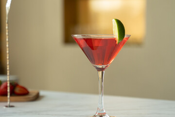 Cosmopolitan cocktail in a martini glass decorated with a slice of lime