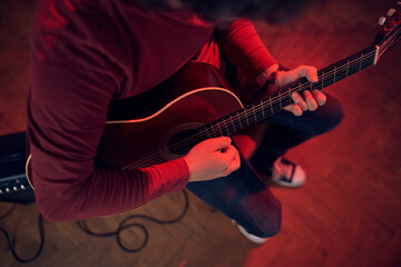 Male musician playing acoustic guitar on the amplifier in retro vintage room.