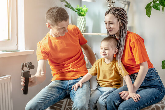 Young modern harmonious family is photographing in bright clothes. Concept of good mood, family care and joint pastime