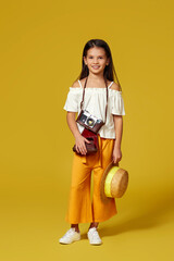 cute little girl with retro camera on yellow background.